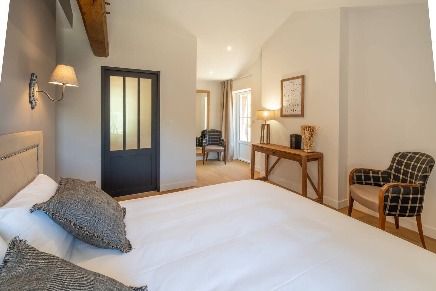 A bedroom with a large bed, a desk, a chair, and a door.