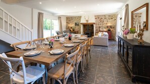 A spacious dining area with a long wooden table set for a meal, flanked by wooden chairs.