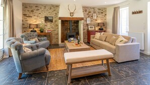 A cozy living room with a stone wall, a fireplace, and a sofa set.