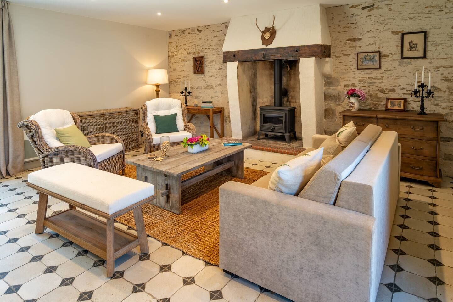 A cozy living room with wicker furniture, a fireplace, and a stone wall.