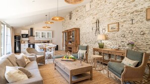 A spacious living room with a sofa, chairs, a coffee table, and a kitchen in the background.