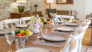 A dining table set with plates, cutlery, and glasses, surrounded by white chairs.