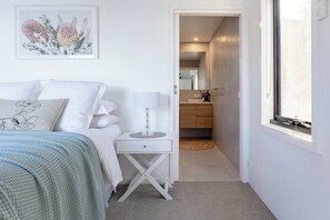 A bedroom with a bed, bedside table, lamp, and a framed artwork on the wall.