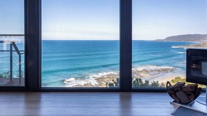 A room with large windows overlooking a coastal view, a wooden floor, and a small table with a decorative item. - The Nook - relaxing home breathtaking ocean views (Wye River)