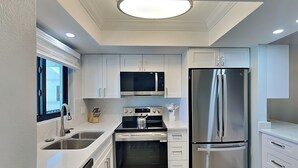 Una cocina moderna con armarios blancos, electrodomésticos de acero inoxidable y una isla central.