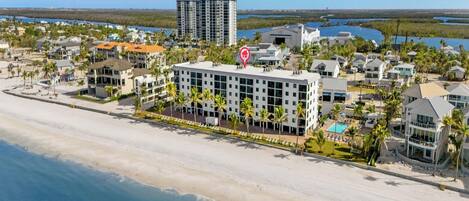 A coastal hotel with a beachfront view, multiple buildings, and a prominent red location marker.