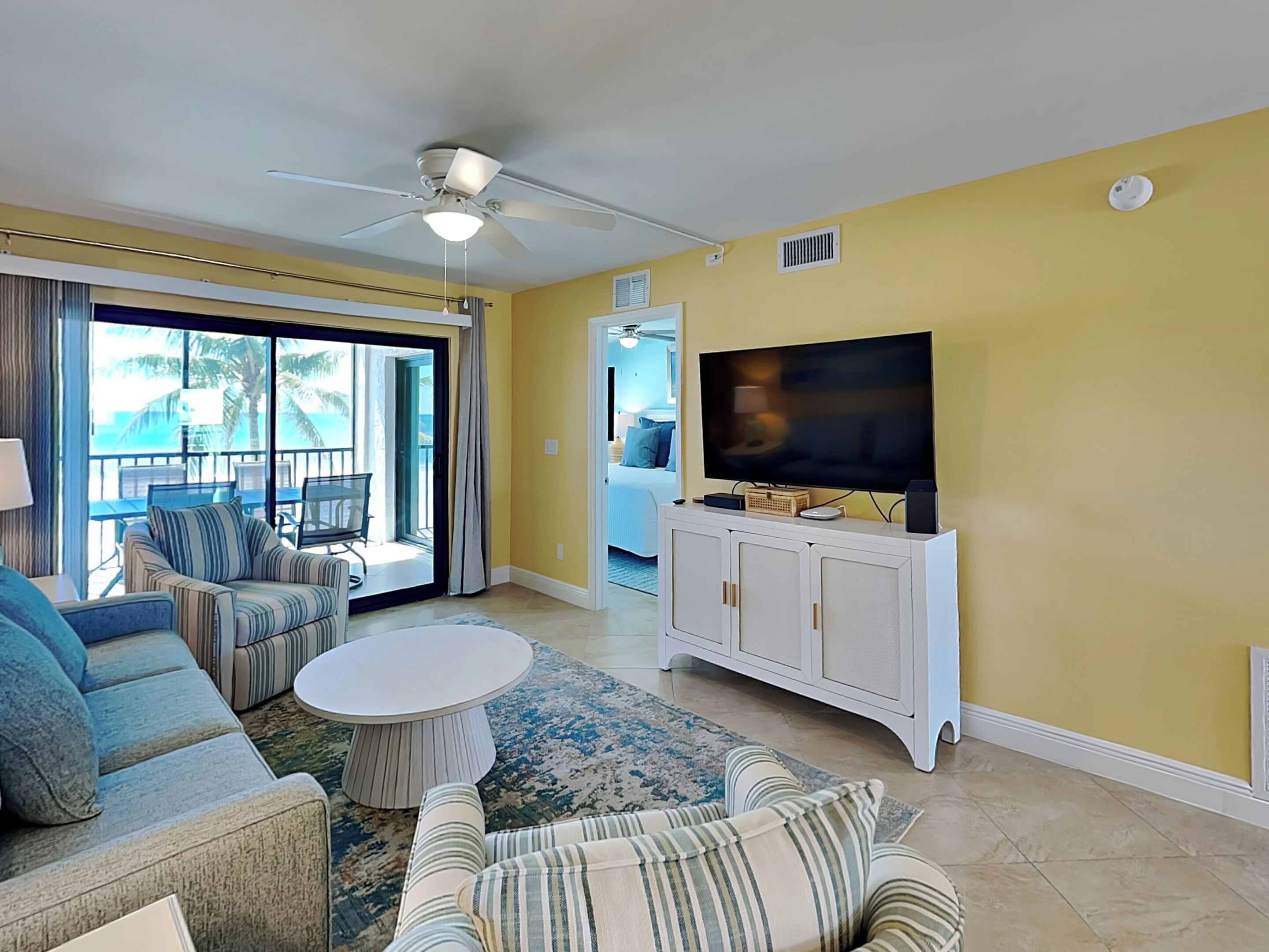 A living room with a TV, sofa, and a balcony with outdoor furniture.