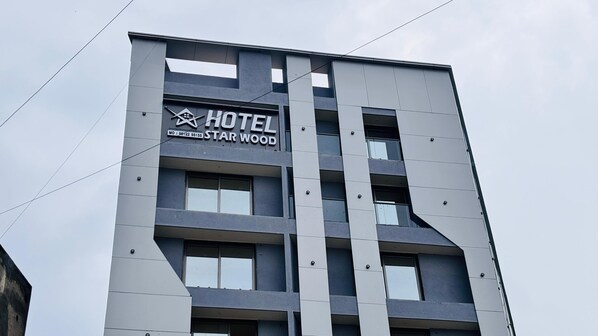 Un immeuble abritant un hôtel à plusieurs étages, sur lequel on peut lire l’inscription « HÔTEL STAR WOOD ».
