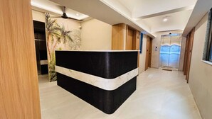 A reception area with a black and white marble counter, wooden paneling, a ceiling fan, and an elevator.