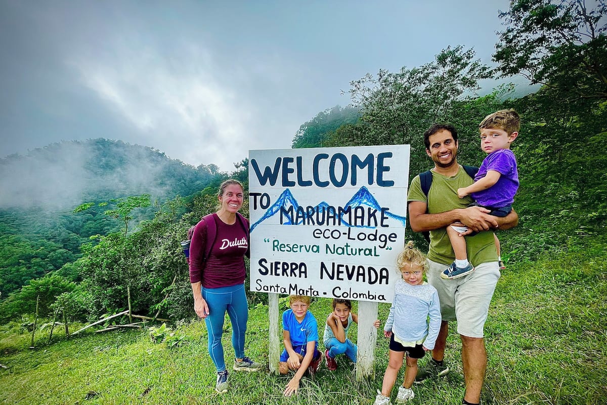 A family standing in front of a welcome sign for Marumake eco-Lodge in Sierra Nevada, Santa Marta, Colombia.