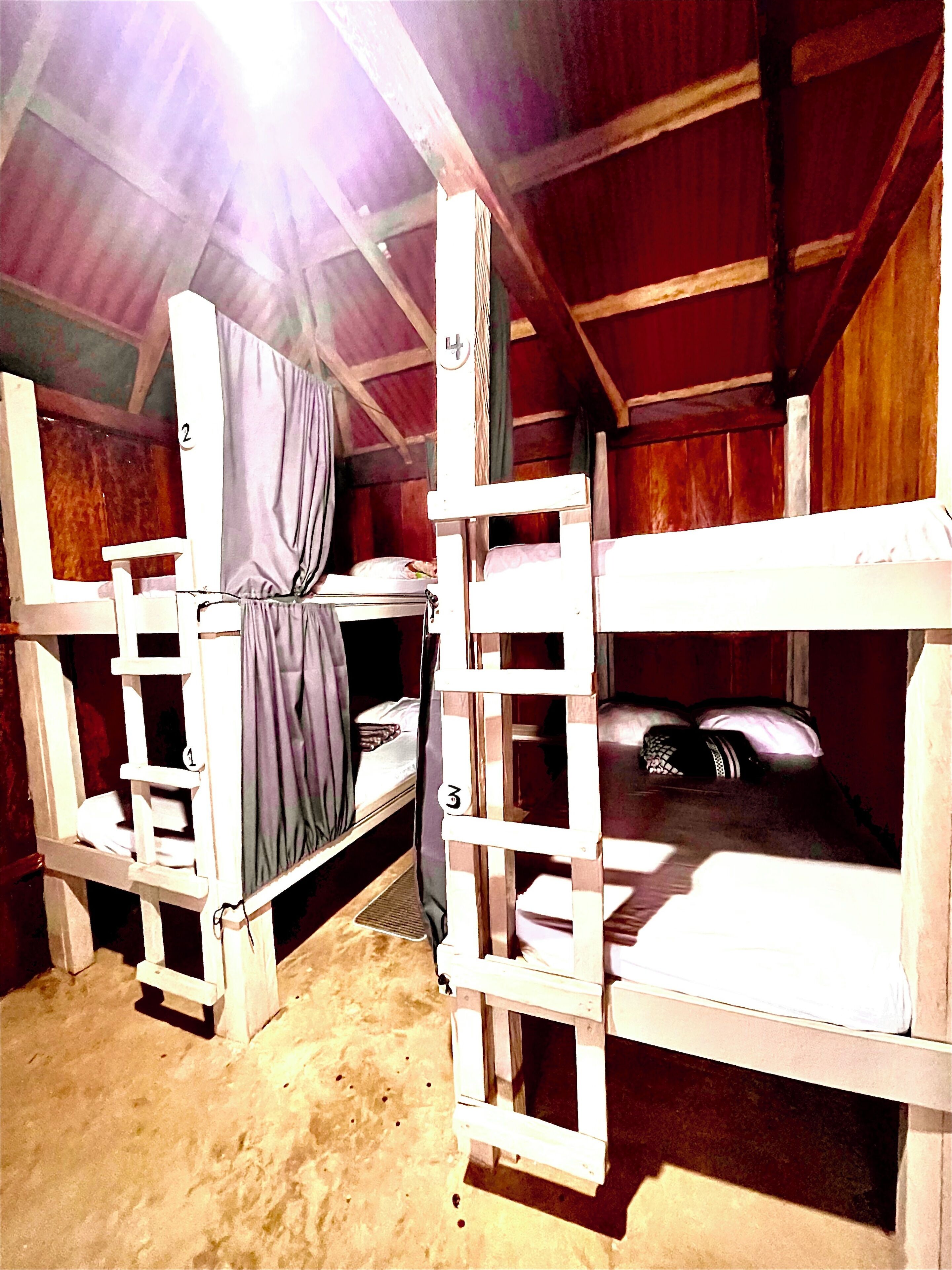 Habitació amb lliteres, una escala i una cortina.