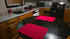 A kitchen with wooden cabinets, a black countertop, a sink, a microwave, and a stove. - Home Away from Home (Chattanooga)