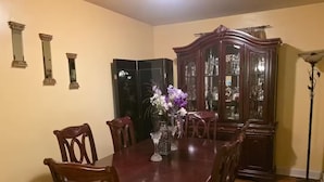 A dining room with a wooden table, six chairs, a vase with flowers, a dark wooden cabinet, and a floor lamp. - Home Away from Home (Chattanooga)