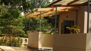 A covered outdoor area with a stone pathway leading to a building with a wooden pergola. - Tranquil forest cabin in Entebbe (Entebbe)