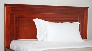 A bed with a wooden headboard and white bedding. - Tranquil forest cabin in Entebbe (Entebbe)