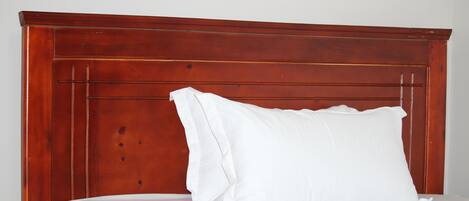 Een bed met een houten hoofdbord en witte beddengoed.