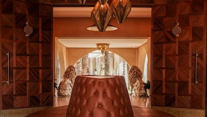 A circular seating area with a tufted, brown leather sofa in the center, surrounded by a wooden wall with geometric patterns. - Loudi Marrakech (Marrakech)