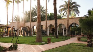 A courtyard with palm trees, a brick pathway, and arches. - Loudi Marrakech (Marrakech)