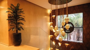 A modern interior with a potted plant, a staircase, and a wall with geometric patterns and a window with a view of palm trees. - Loudi Marrakech (Marrakech)