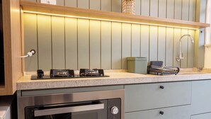 A kitchen with a built-in oven, a gas stove, and a stainless steel sink. - Confort vel Apartamento com Wi-fi p na Areia (Santos)