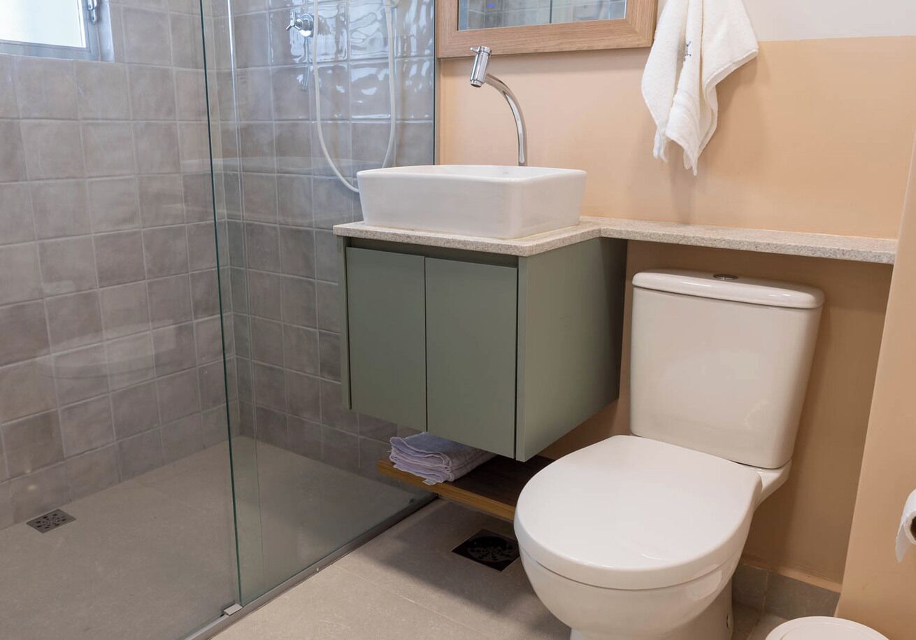 A bathroom with a glass-enclosed shower, a white sink, and a toilet.