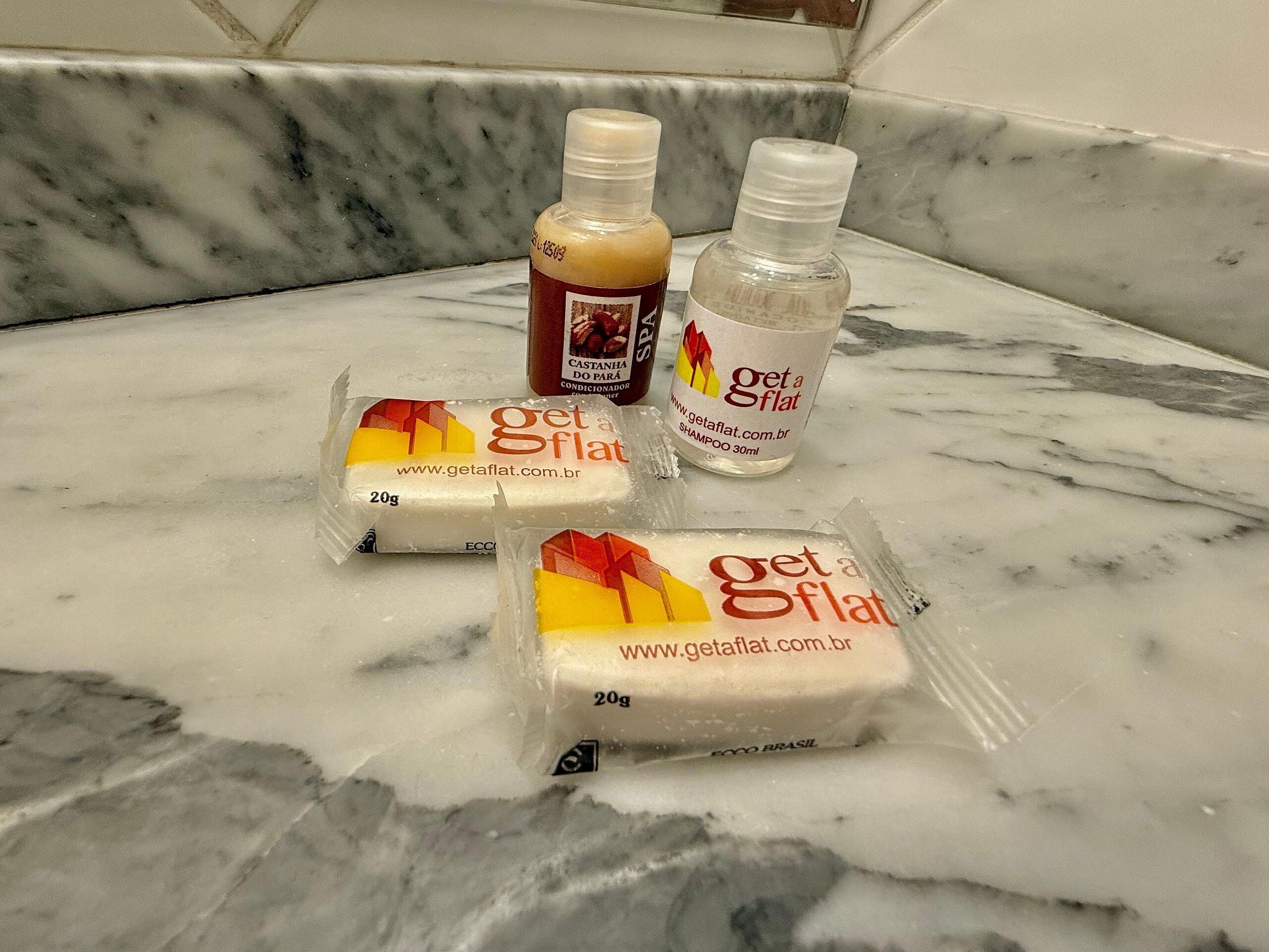 Drie Get a Flat shampoos en twee Get a Flat zeepstaven op een marmeren aanrecht.
