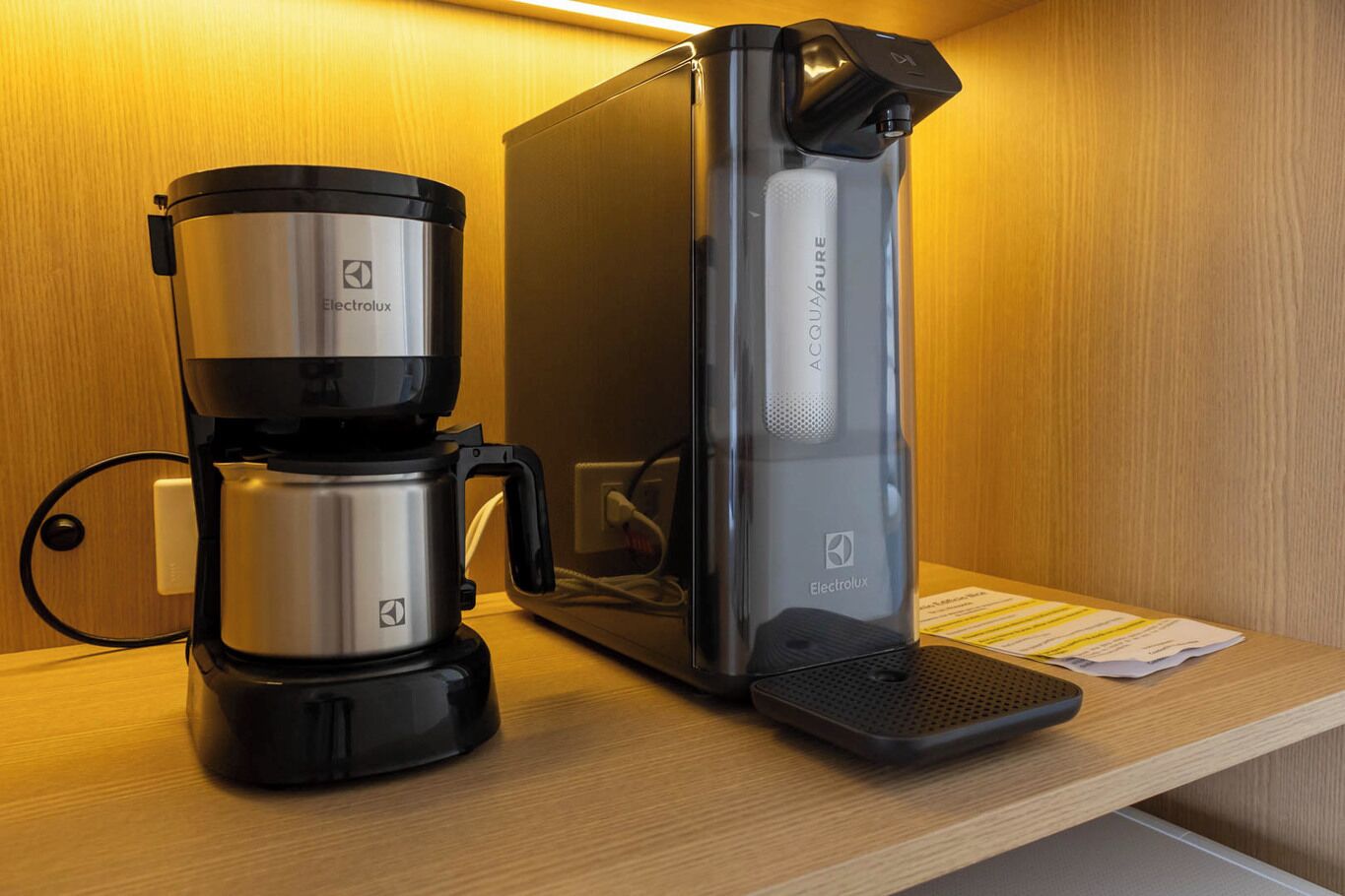 A coffee maker with a water reservoir and a drip tray on a wooden surface.