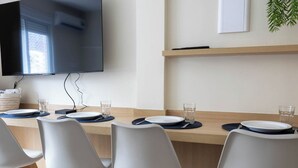 A conference room with a long table, white chairs, and a flat-screen TV mounted on the wall.