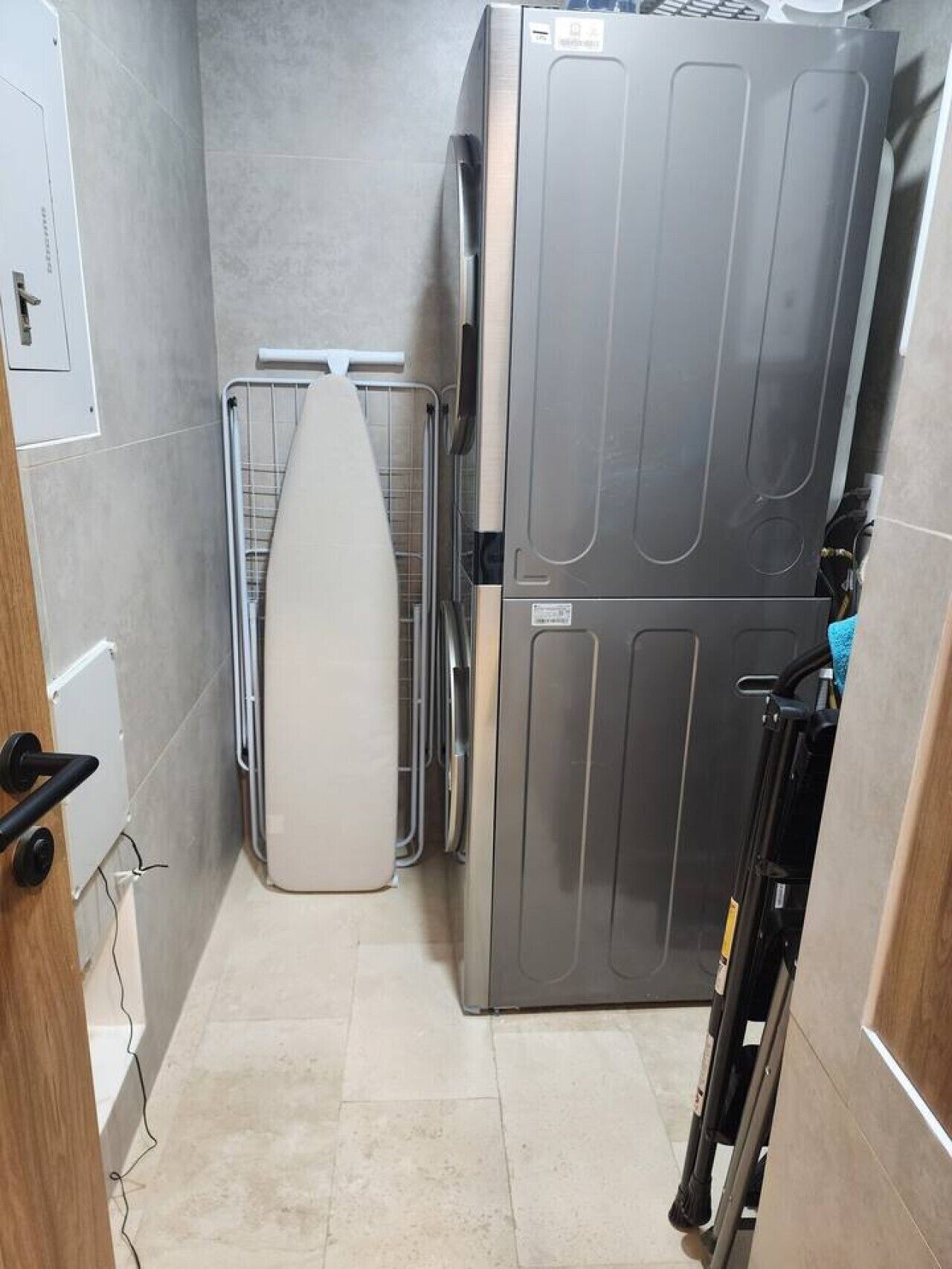 A compact kitchen with a built-in oven, a drying rack, and a small ironing board.