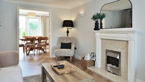 A living room with a fireplace, a dining area with wooden furniture, and a modern lamp.