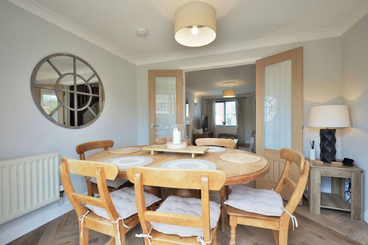 A dining area with a round table, six wooden chairs, and a central light fixture.