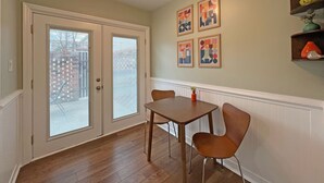 A dining area with a table and chairs, a ceiling light, and a wall with framed artwork. - Modern Hickory Hideaway (Hickory)