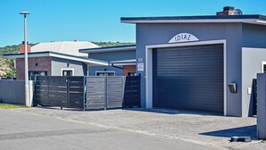 A modern building with a garage door labeled "IDIAZ" and a brick wall. - Diaz Guesthouse (Mossel Bay)