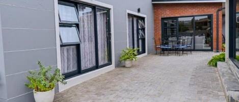 A modern building with a paved courtyard, large windows, and outdoor seating area.