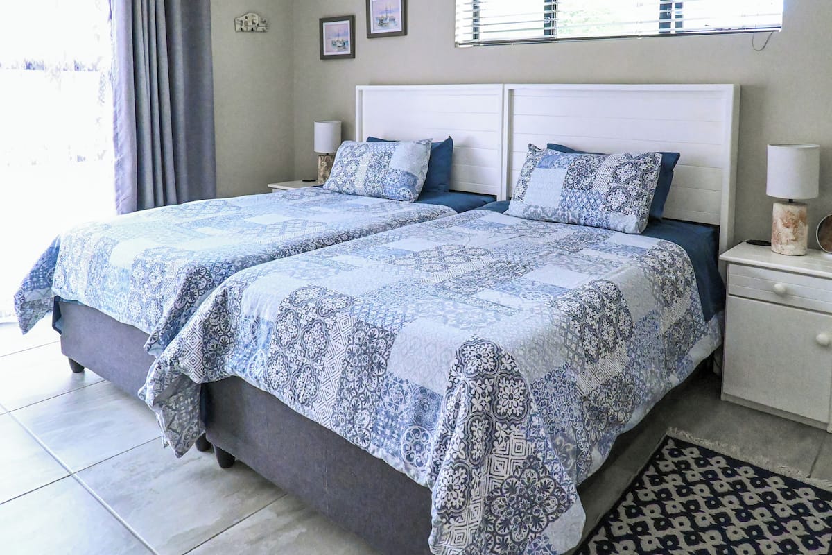 A double bed with patterned bedding, a bedside table with a lamp, and a patterned rug.