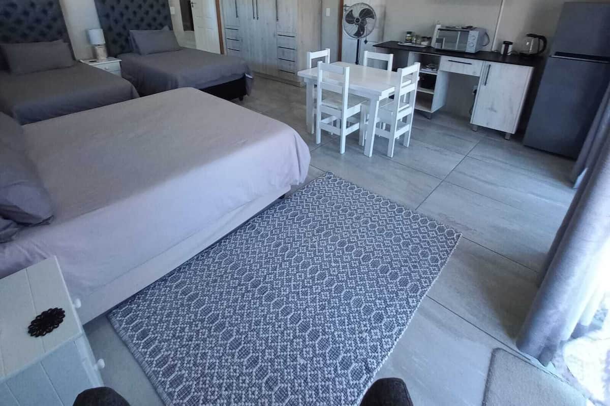 A hotel room with two beds, a kitchenette, a dining area, and a TV.