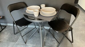Ett matbord med fyra skålar och två koppar, omgivet av två svarta stolar.