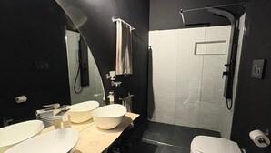 Ett modernt badrum med en stor spegel, tre tvättställ, en toalett och en dusch.