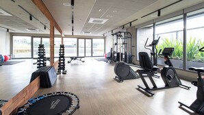 Un'ampia palestra con diverse attrezzature per esercizi, ampie finestre e un soffitto in legno.