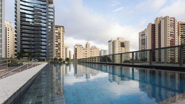 Una piscina con bordo piastrellato, circondata da edifici residenziali alti.