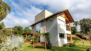 A modern two-story house with a covered porch, a garage, and a well-maintained garden. - Casa de Campo c Wi-fi Jardim e Churrasqueira (Benedito Novo)
