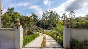 A pathway leading to a building with a gated entrance, surrounded by greenery and trees. - Casa de Campo c Wi-fi Jardim e Churrasqueira (Benedito Novo)