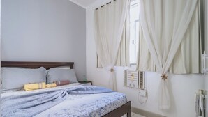 Ein Schlafzimmer mit Bett, Vorhängen, einem Nachttisch und einem Wandheizkörper.