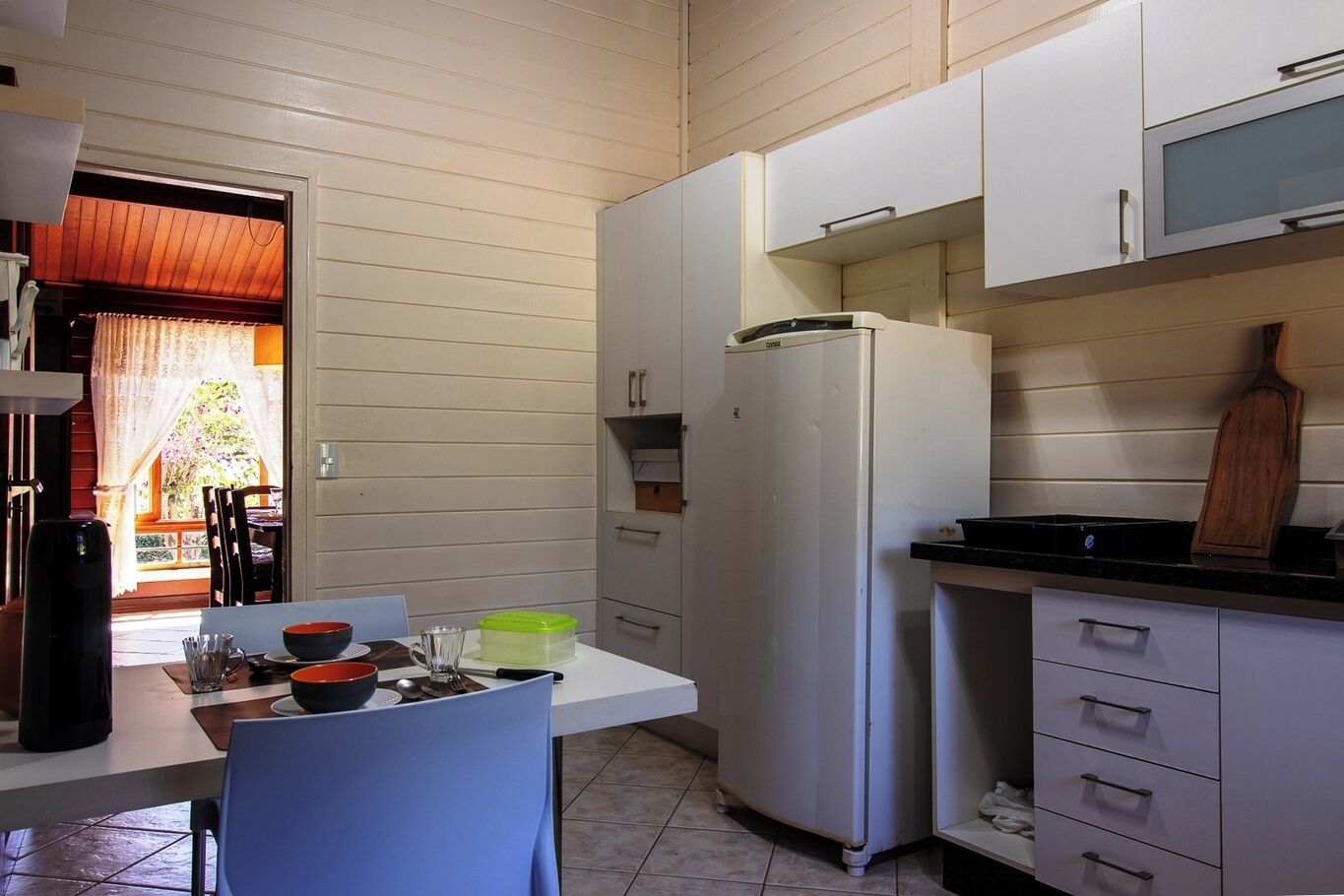 A compact kitchen with white cabinets, a refrigerator, and a dining area with a table and chairs.