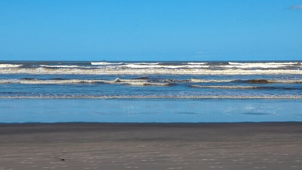 Una spiaggia con onde e cielo sereno.