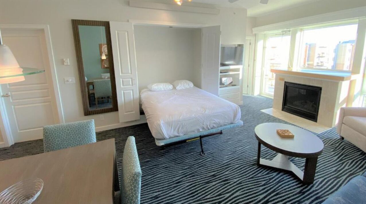 Una camera d'albergo con un letto, una TV, un camino e vista sulla città.