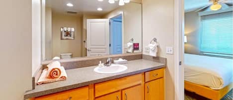 A hotel bathroom with a sink, mirror, and wooden cabinets.