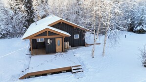 A cabin with a wooden exterior, a sloped roof, and a front porch.