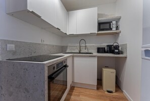 Una cocina compacta con horno integrado, microondas y refrigerador pequeño.