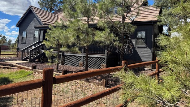 Une maison à deux étages avec une terrasse en bois et une cour clôturée.